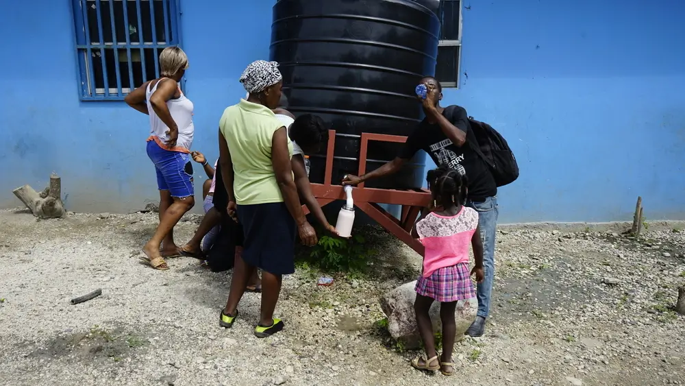 Habitantes del campo para desplazados en Puerto Príncipe, toman agua de los tinacos que instaló MSF.