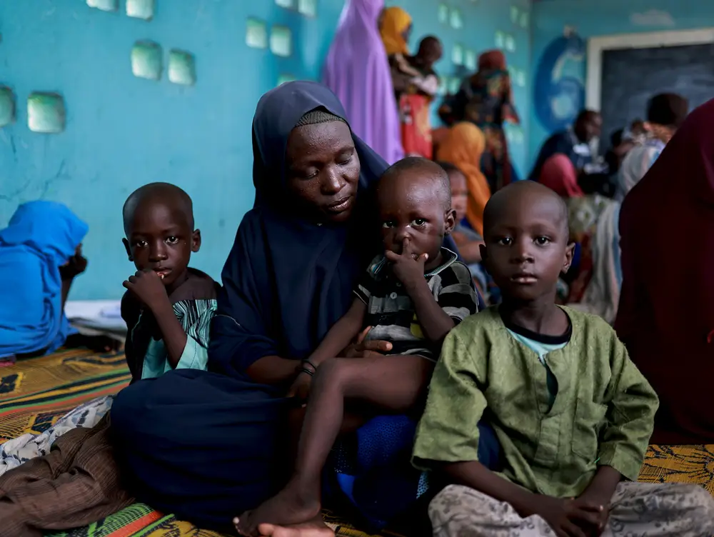 Baana y sus hijos sentados en la clínica móvil de MSF en el campamento de Teachers Village, en Maiduguri, Nigeria. Son algunas de las personas afectadas por las inundaciones.
