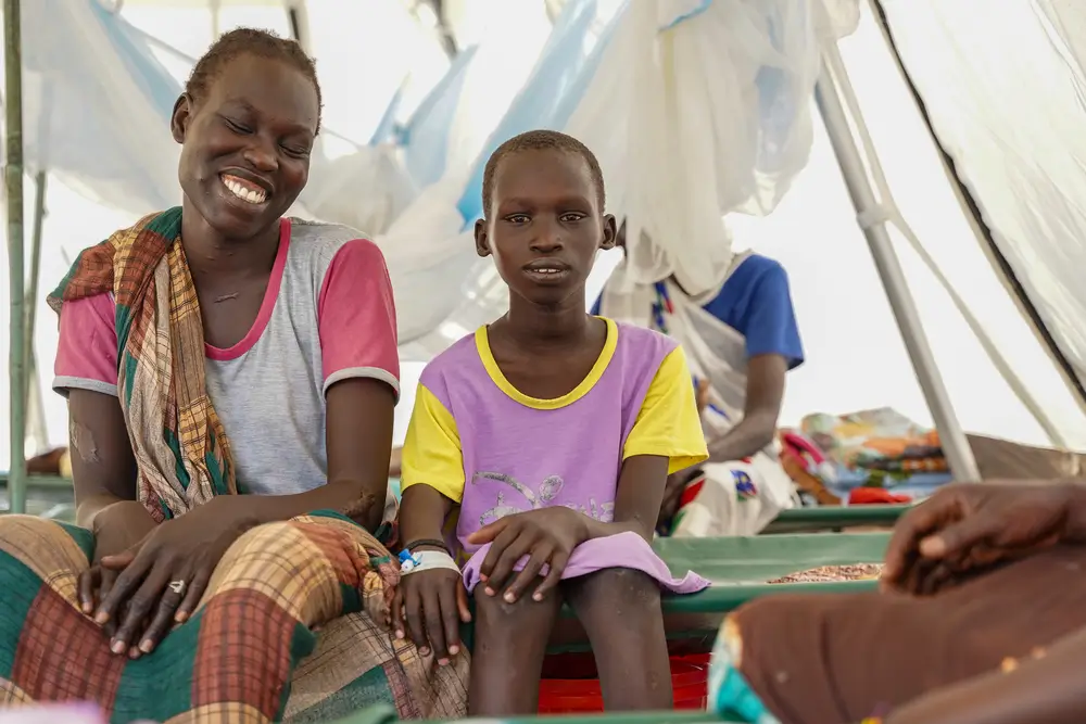 Sunday Willian, de 29 años, sentada junto a su hija, Amani Peter, de 9 años, en una de las tiendas de campaña del Centro de Tratamiento del Cólera (CTC) de Assosa.