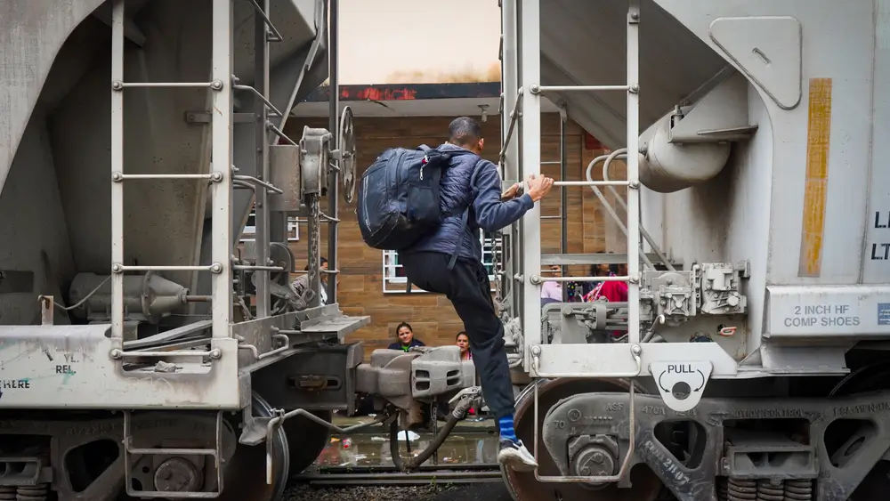 Hombre migrante en la frontera sur de México sube al tren que lo llevará a la frontera norte del país.