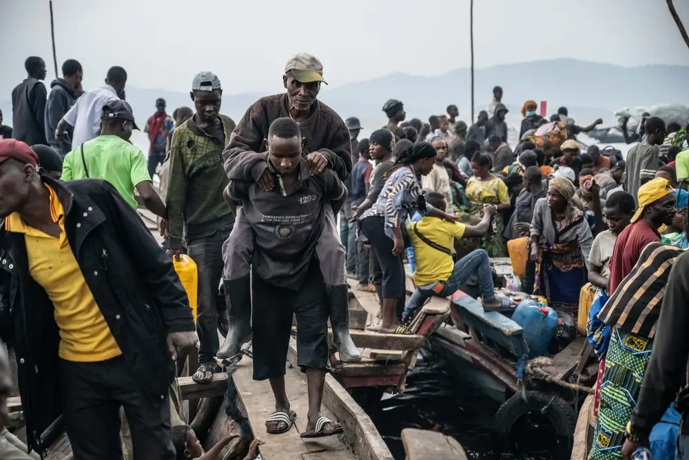 Un hombre es rescatado de un barco que llegó al puerto de Kituku, en Goma, y que transportaba a personas que huían de los combates que se están librando en Kivu del Norte y Kivu del Sur. Provincia de Kivu del Norte, República Democrática del Congo, enero de 2025.