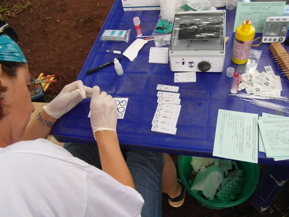 Un técnico de laboratorio, que viaja con un laboratorio móvil, que incluye microscopios y centrífugas, analiza una muestra de sangre para detectar la enfermedad del sueño, una de las Enfermedades Tropicales Desatendidas. República Democrática del Congo, agosto de 2015.© Philipp Frisch/MSF