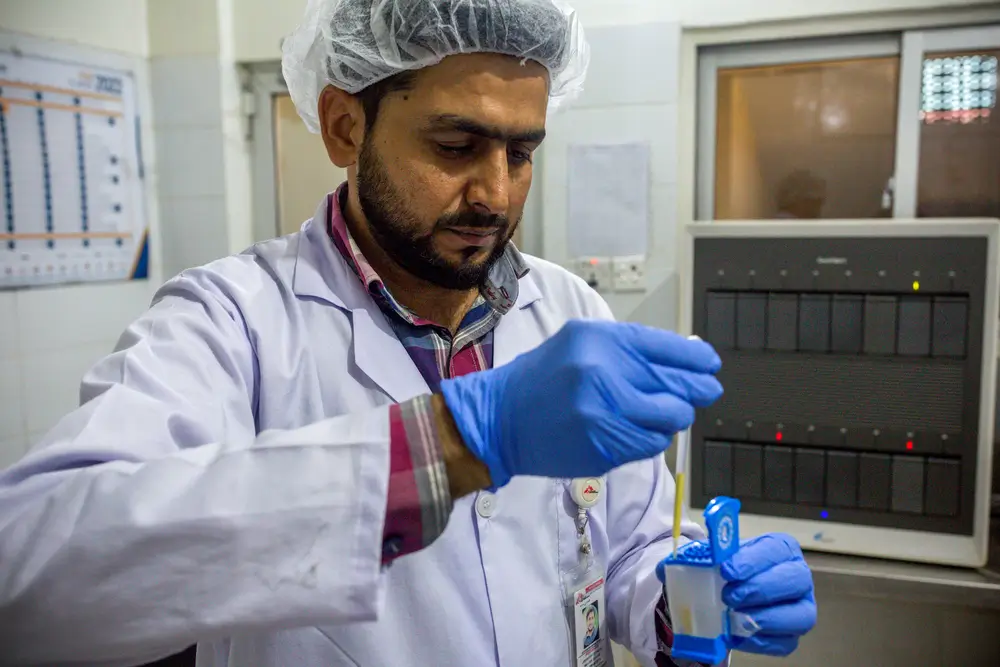 Un técnico de laboratorio capacitado prepara cuidadosamente un cartucho para realizar pruebas precisas de hepatitis C con GeneXpert® en la clínica de MSF en Machar Colony, Karachi, Pakistán.
