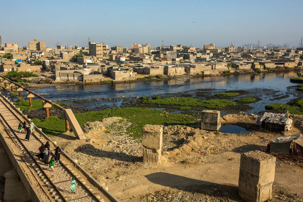 Mujeres y niños caminan por un puente ferroviario de la línea circular de Karachi (KCR), junto al asentamiento informal de Machar Colony en Karachi, Pakistán