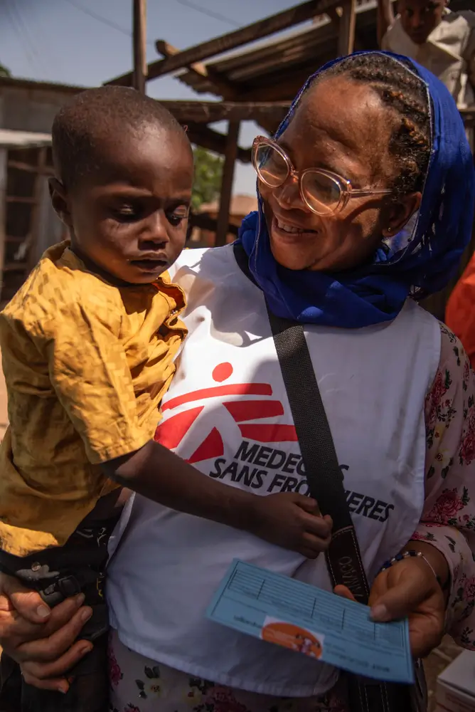 Mercy sostiene a Mohammed Ismael, de cuatro años, mientras recibe su calcomanía y certificado tras recibir la vacuna Penta-5 como parte de la campaña de vacunación masiva lanzada recientemente en Sokoto.