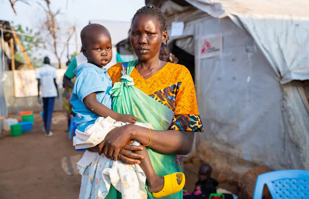 Nyaluak Kuol saliendo del centro de tratamiento del cólera en Sudán del Sur con su hijo de dos años, Tesloach Manah, que fue admitido.