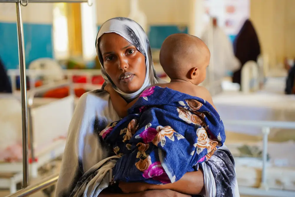 Suado Hassan Mohamed, de 22 años, sostiene a su hijo de 11 meses, Abdirahman Abdilatif, en la sala pediátrica del Hospital Regional de Bay, apoyado por MSF. Suado, residente de Baidoa, trajo a su hijo para que recibiera tratamiento, ya que actualmente recibe atención por desnutrición.
