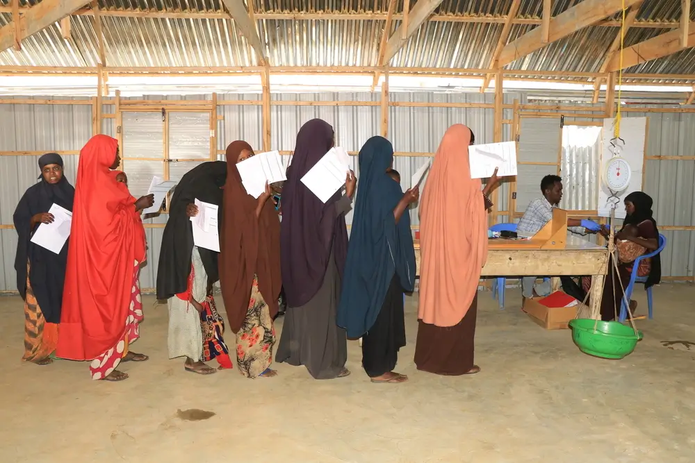 Un grupo de madres hace fila para medir la altura y el peso de sus hijos y recibir un suplemento nutricional listo para usar en el centro de atención descentralizado apoyado por MSF cerca del campamento de desplazados internos de Eelbet-I, en Baidoa.