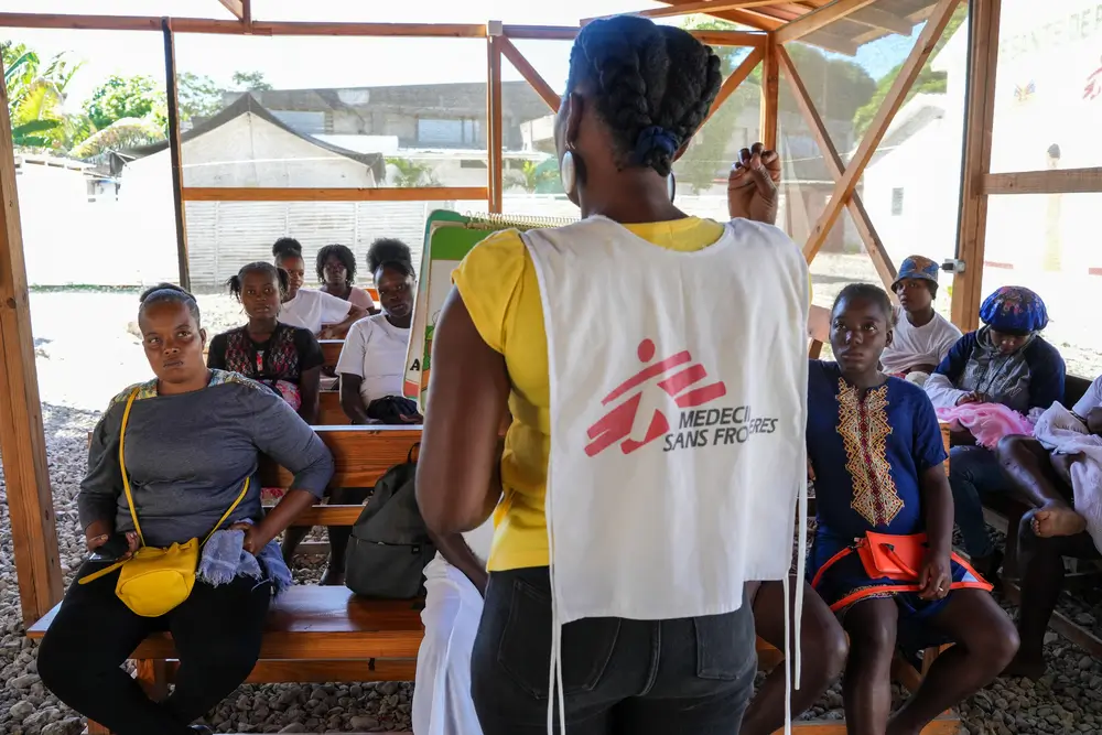Una promotora de salud habla con pacientes en la sala de espera del hospital de maternidad de Port-à-Piment. Estas sesiones ayudan a informar a las pacientes sobre temas esenciales, como la planificación familiar, la higiene, la violencia sexual, la importancia de los controles prenatales regulares y las señales de alerta durante el embarazo.