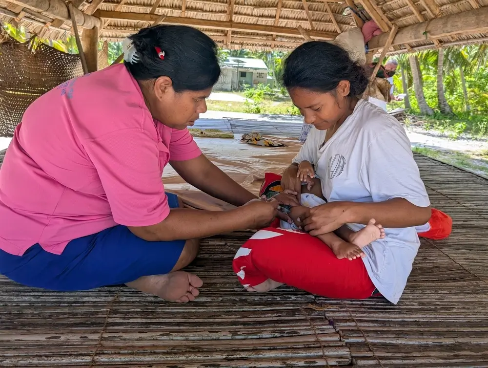 Un niño recibe antibióticos administrados por Batiua, asistente médico, dos días después de ingresar en la clínica. Esta fue la última dosis que se le administró. Kiribati, enero de 2025.