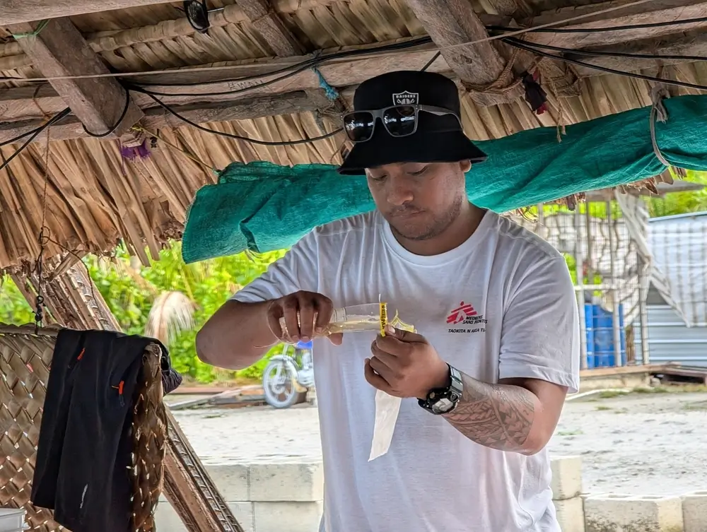 Mila Tirikai, supervisora de agua y saneamiento de MSF, vierte una muestra de agua de pozo en una bolsa de clorofila para una prueba de coliformes fecales. Kiribati, enero de 2025.