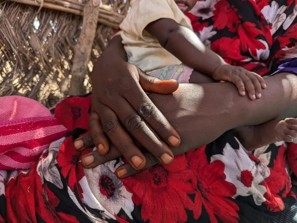 Las manos de Nour, que sostiene a su bebé en brazos.