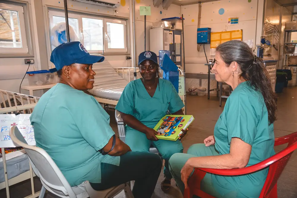 Randi Movich, directora pedagógica de la Academia de Salud de MSF, observa una conversación sobre higiene de manos entre dos participantes tras una observación en el centro de nutrición terapéutica para pacientes hospitalizados, dentro del hospital maternoinfantil de MSF en el distrito de Kenema. Sierra Leona, mayo de 2025.