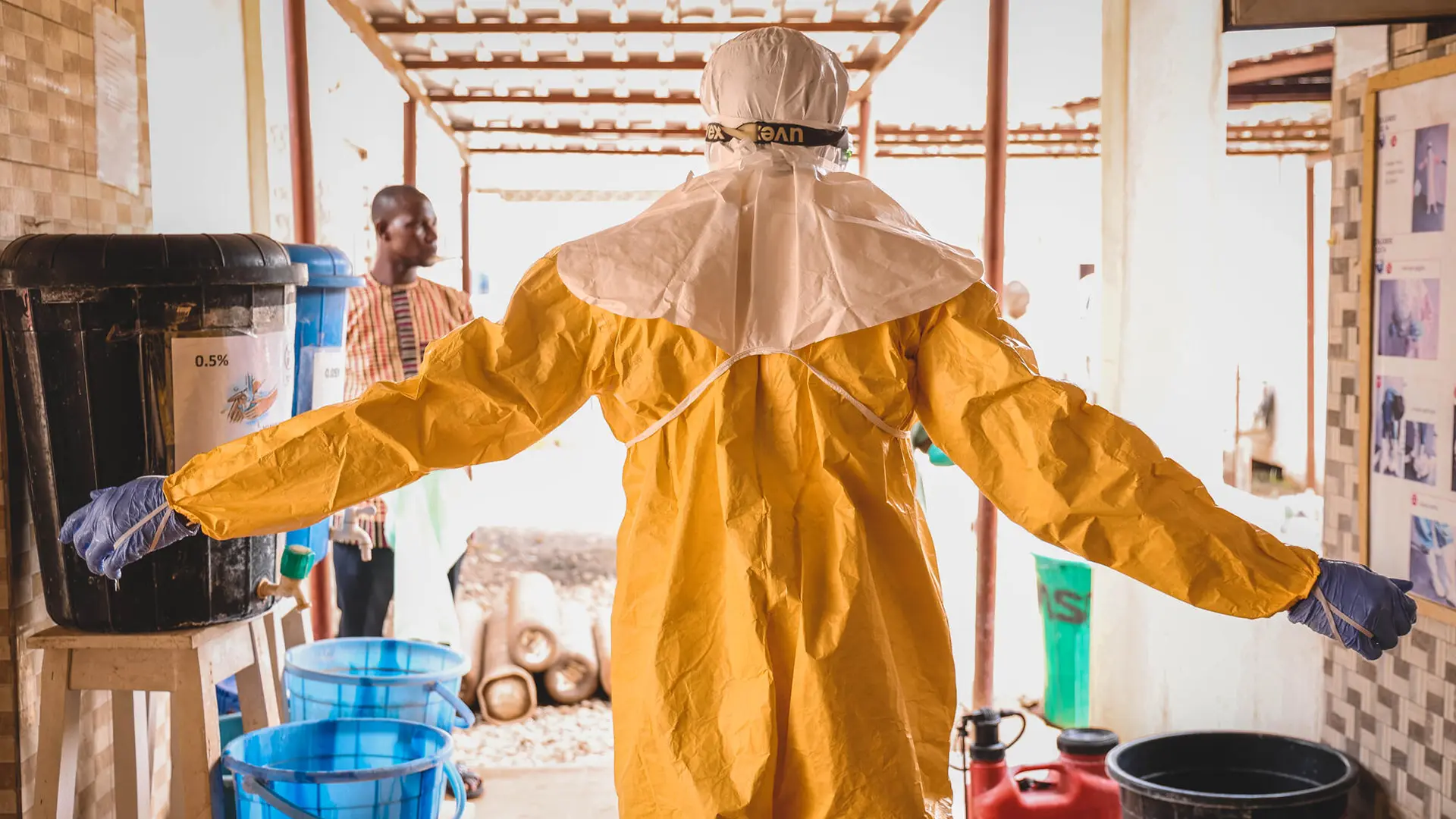 Un médico de MSF levanta las manos mientras lo rocian con cloro diluido en agua tras una ronda de guardia en la unidad de virología del Hospital Universitario Federal Alex Ekwueme en Abakaliki, estado de Ebonyi. Nigeria, marzo de 2023.