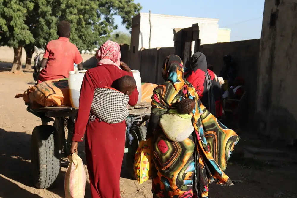Dos mujeres después de recibir sus canastas de alimentos, comenzando su viaje a casa en carro tirado por burros. Darfur Sur, Sudán.
