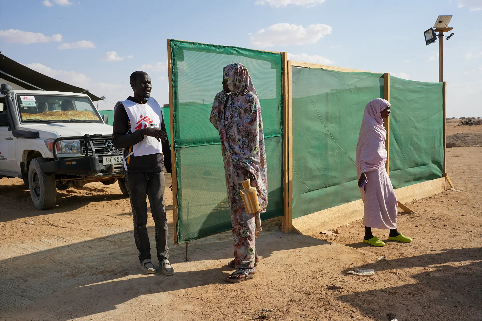Un guardia habla con alguien fuera del puesto de salud del campamento de tránsito de Tine. Chad, junio de 2025.