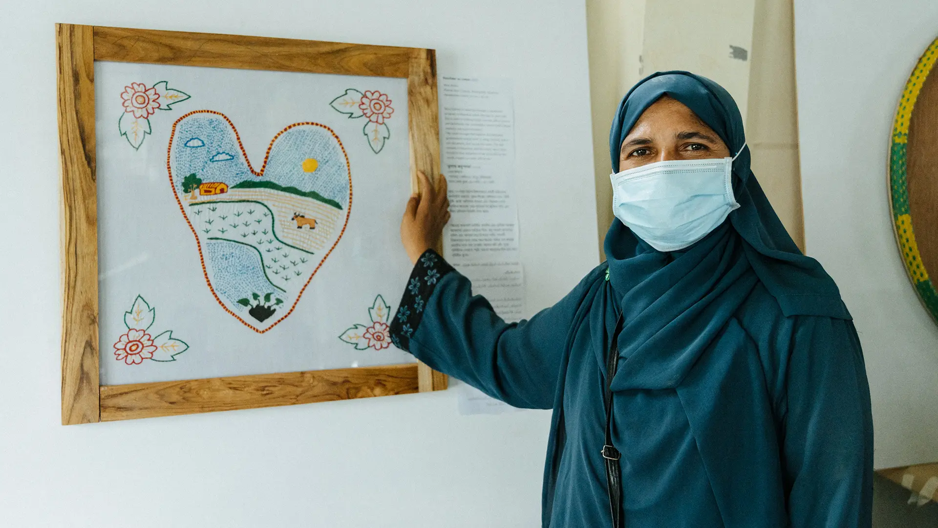 Senu Anara, refugiada rohingya junto a su obra, dibujo de una hoja de taro.