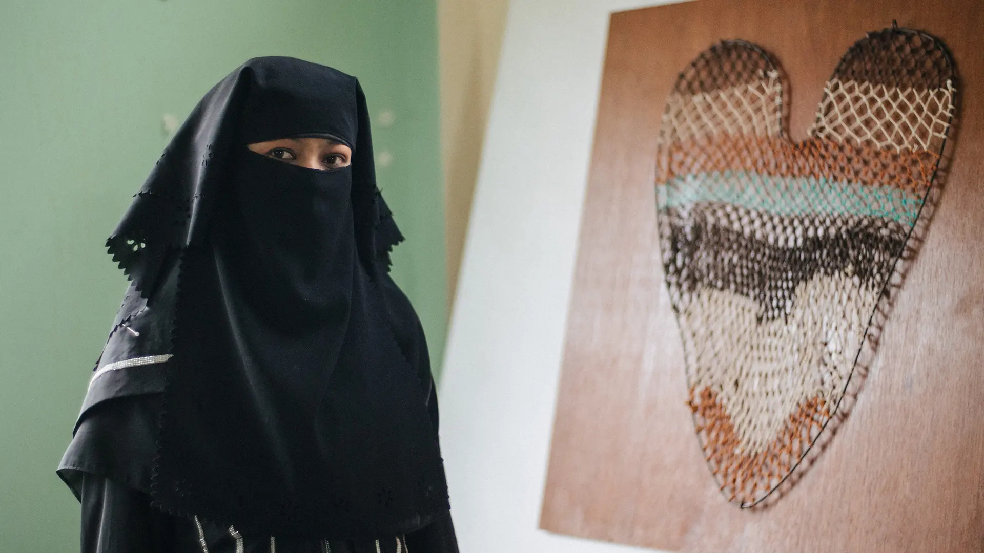 La tejedora rohinyá Nuru Sabar junto a su obra de arte con hojas de taro tejidas en red.