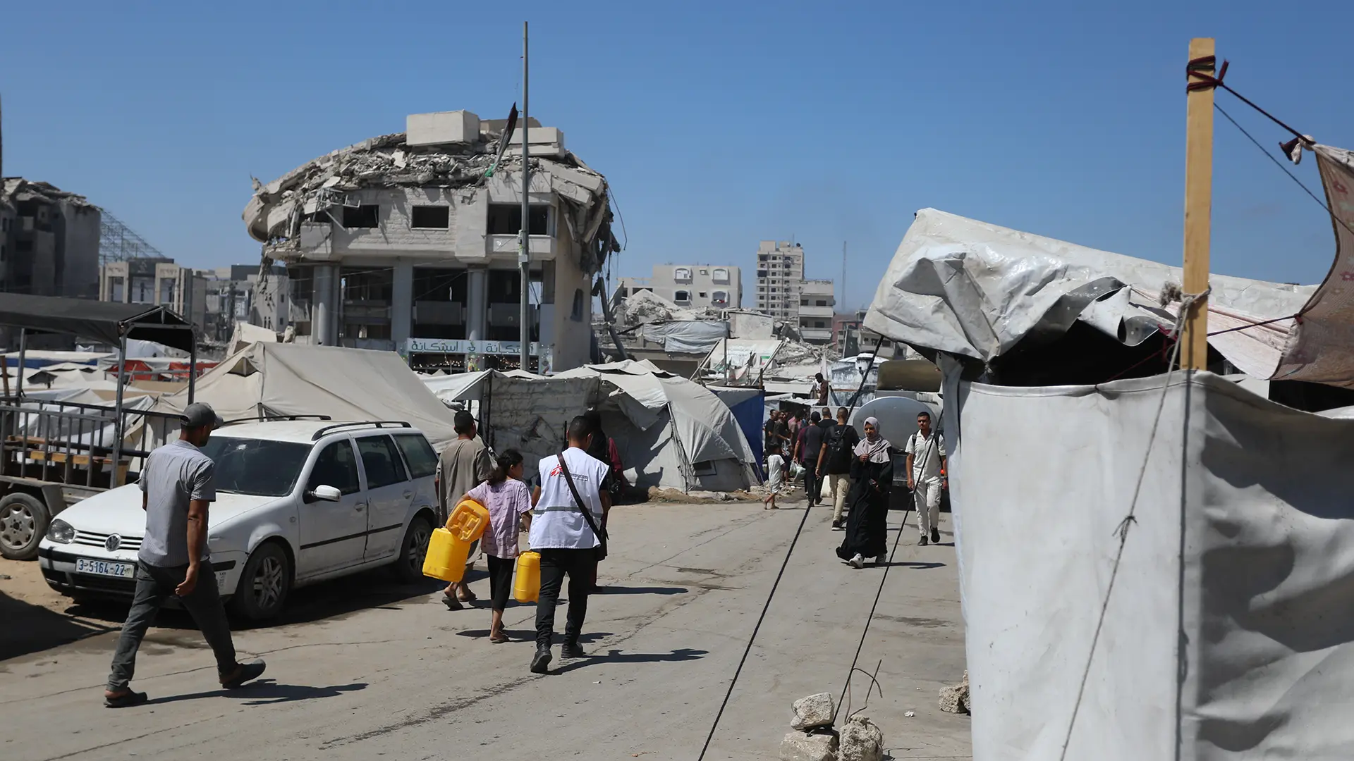 Un trabajador de agua y saneamiento de MSF ayuda a una niña a cargar su bidón lleno.