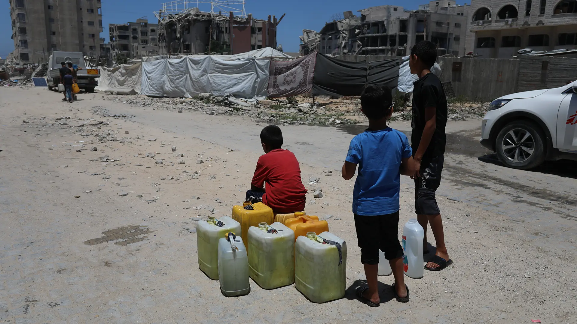 Niños esperan junto a sus bidones vacíos la llegada de un camión cisterna a la ciudad de Gaza.