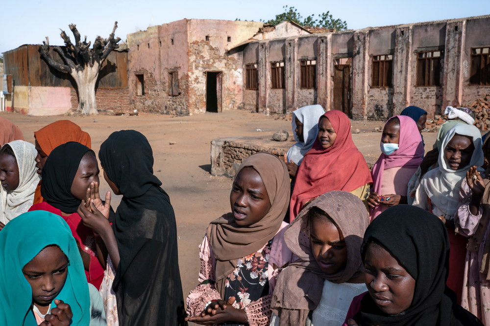 Niños y niñas se reúnen al comienzo de una jornada escolar en la escuela primaria de Alkasim. La escuela destruida en El Geneina, Darfur Occidental, Sudán.