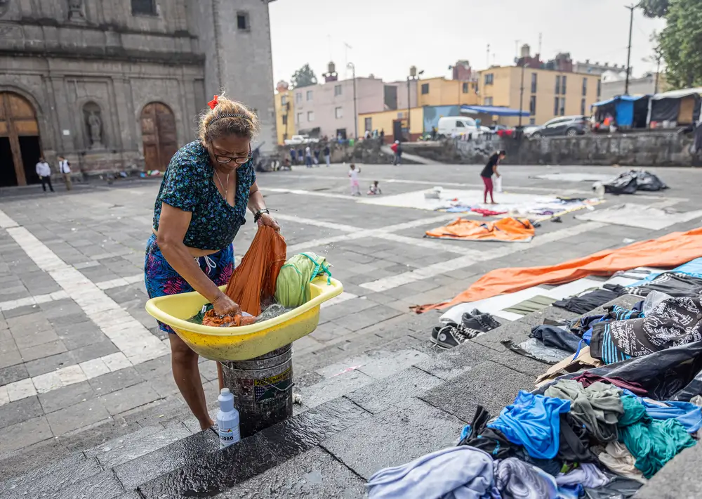 Una mujer migrante lava ropa en la Plaza de la Soledad, Ciudad de México.