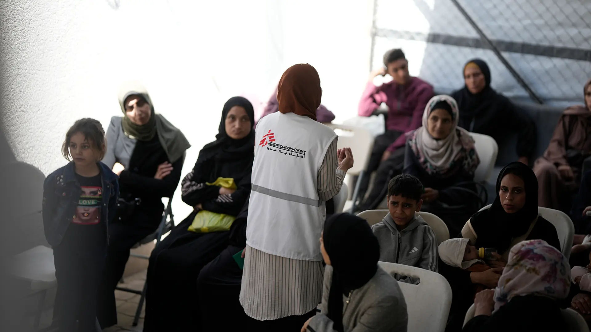 Una trabajadora de salud comunitaria de MSF explica a los pacientes los datos sobre la desnutrición antes de ingresar para el chequeo en la clínica de MSF en Gaza, en la ciudad de Gaza.