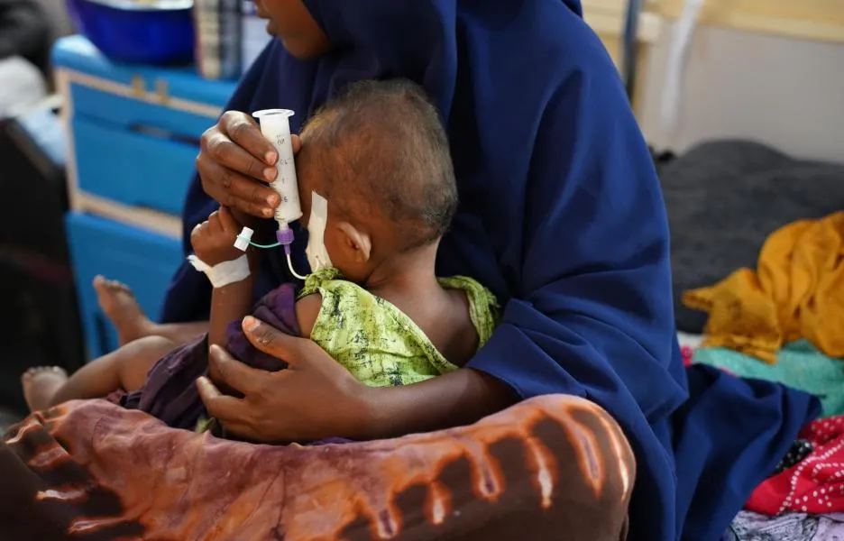Una mujer sostiene a su hijo, quien sufre desnutrición, y le alimenta con una jeringa en el Hospital Bay Regional que apoyamos en Baidoa, en Somalia.