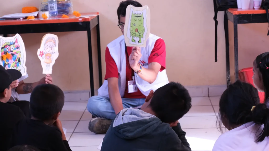 Niños observan la obra "El monstruo de colores" donde aprenden de gestión de emociones y salud mental. Hidalgo, México, 2025.