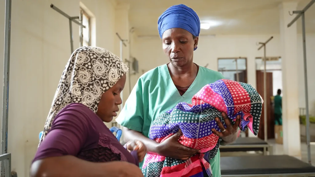 Antoinette ayuda a una madre a sostener a su bebé en la sala de maternidad del hospital de MSF en el campo de Nduta. 