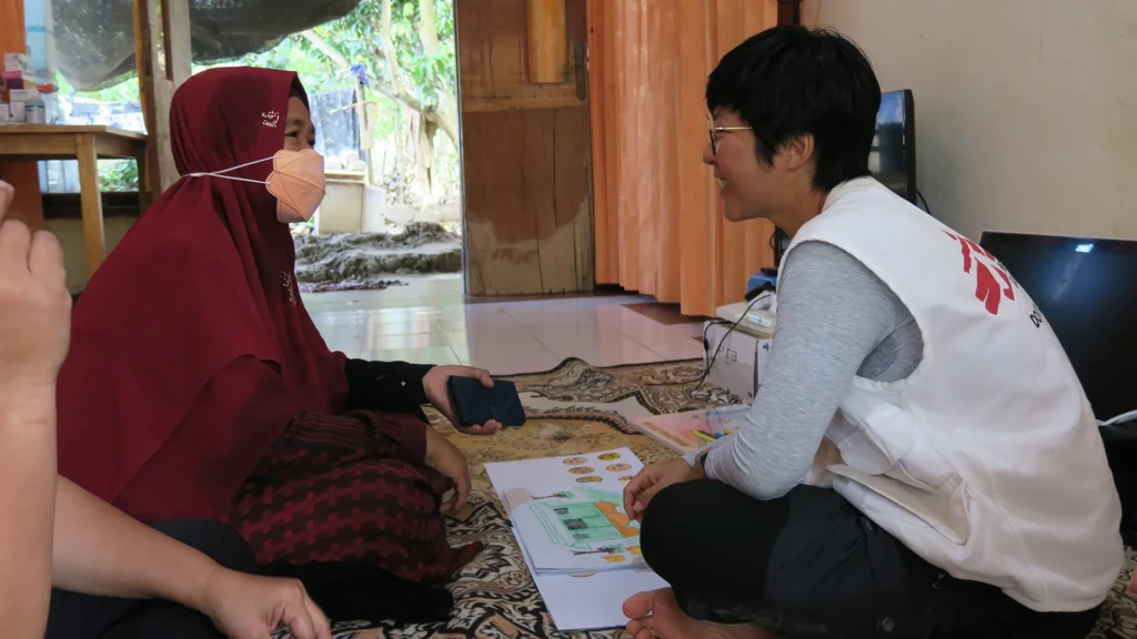 Un miembro del personal de salud mental de MSF interactúa con una paciente durante una actividad de salud mental en Desa Sekerak, Aceh, Tamiang.